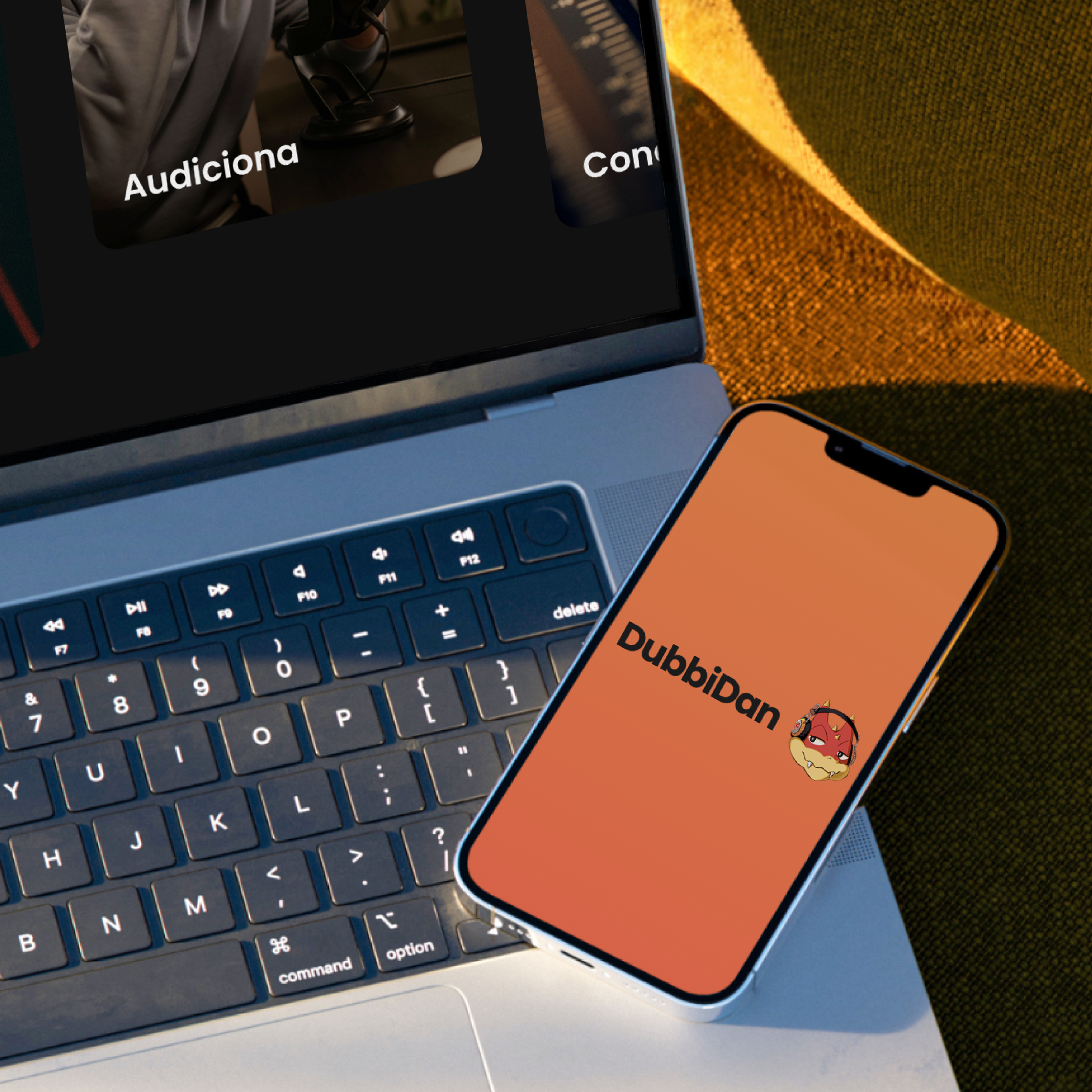 The DubbiDan wordmark and mascot on a phone, resting against a laptop