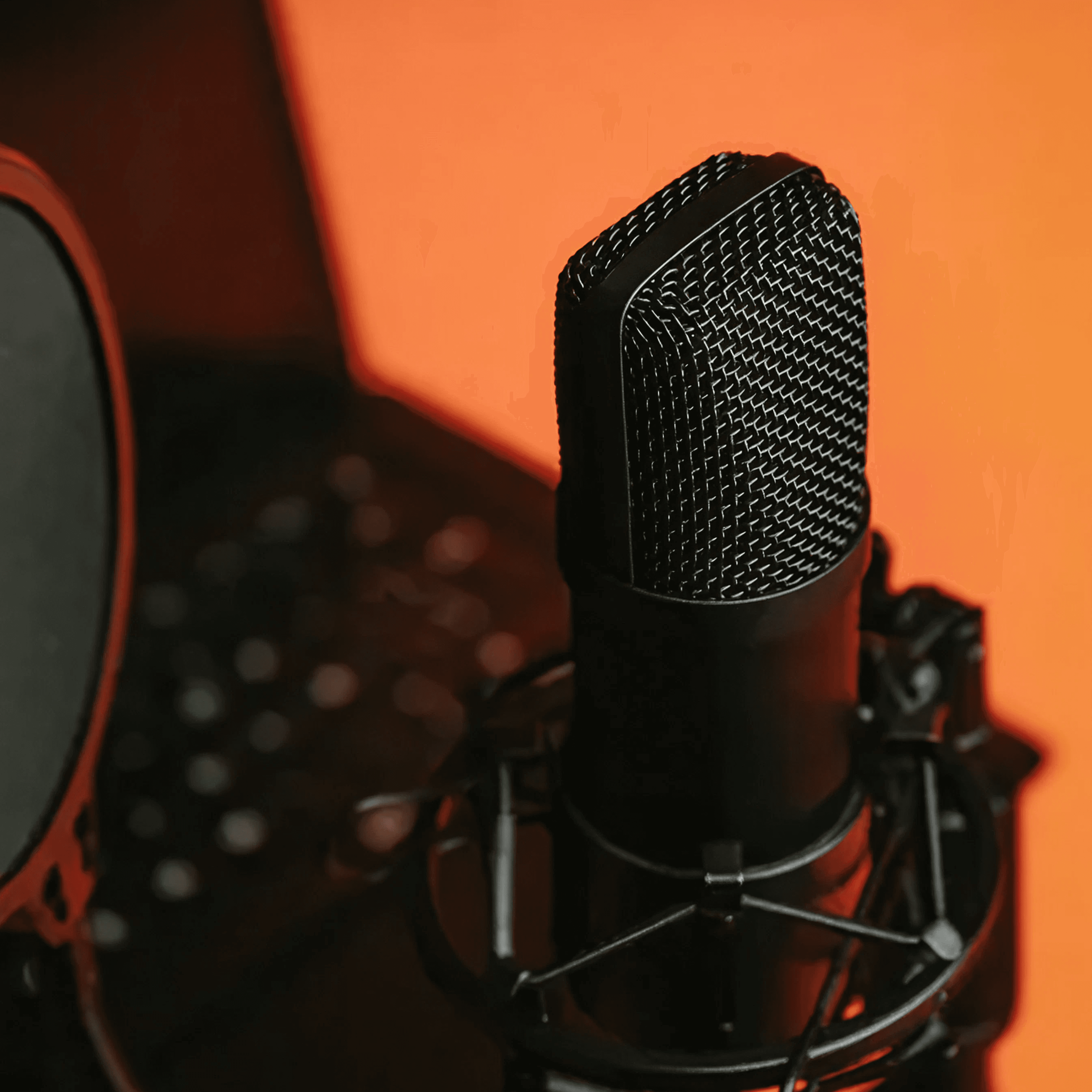 A condenser microphone lit against a warm orange backdrop