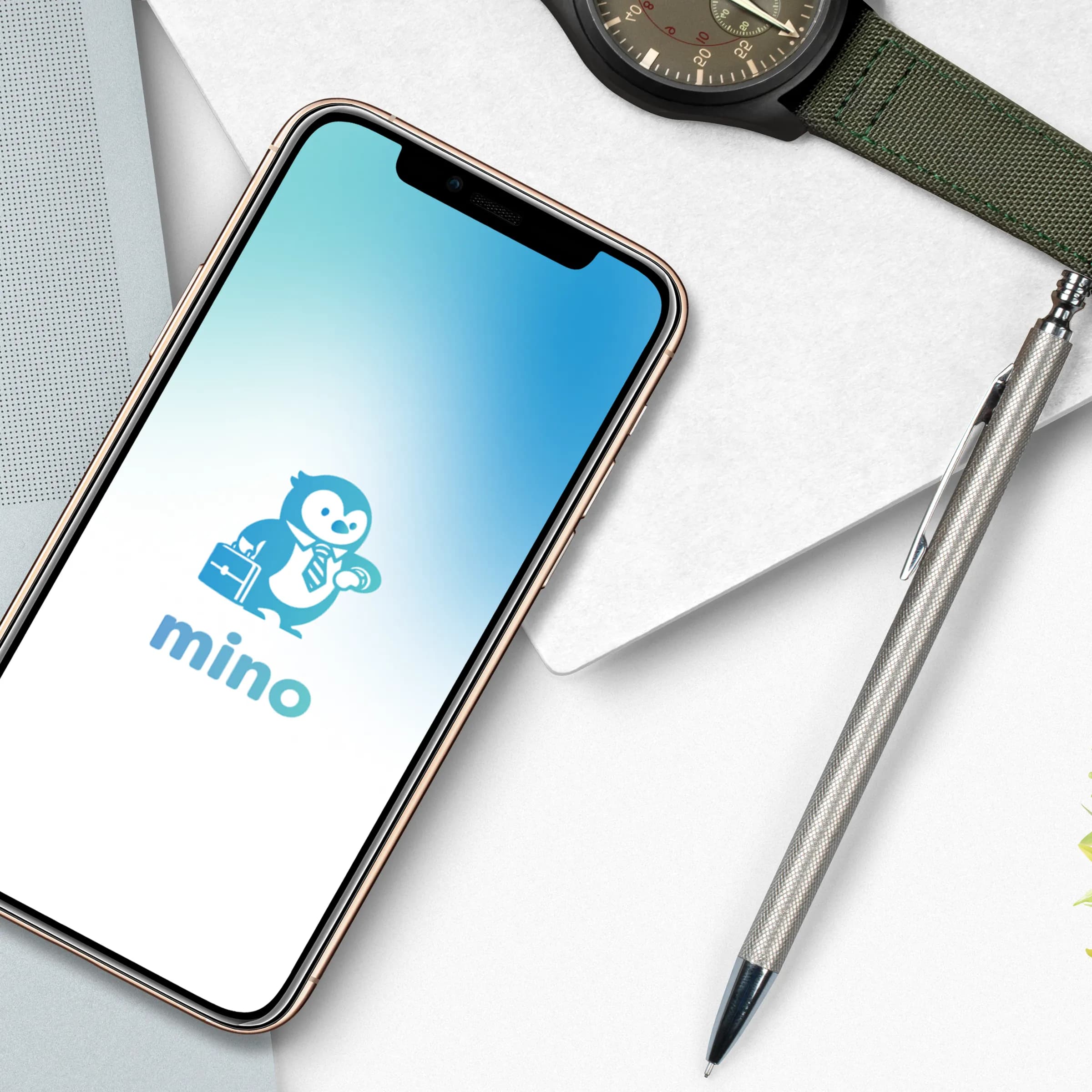 The mino splash screen, the penguin mascot with its briefcase, on a phone resting on a desk