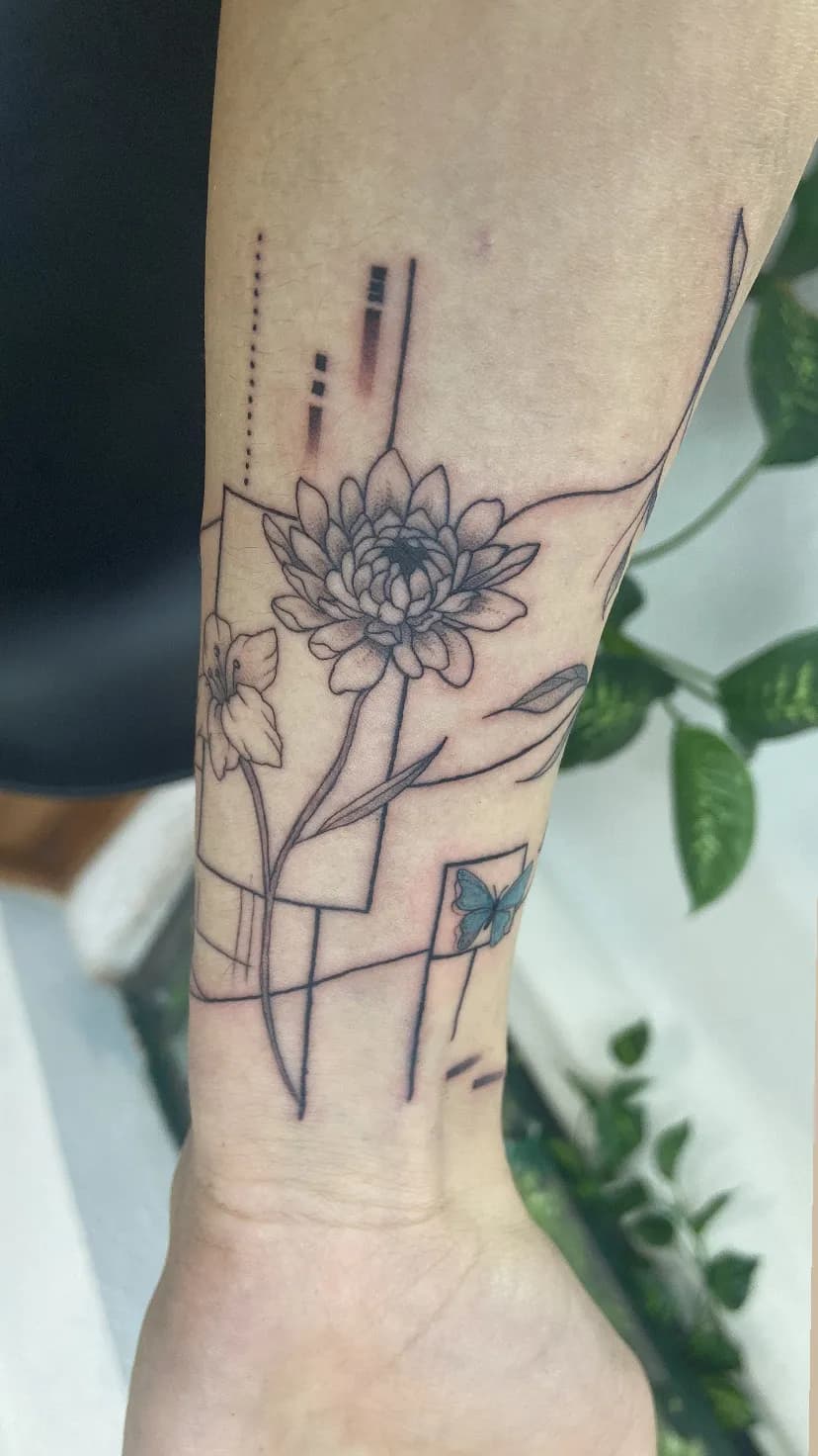 A forearm tattoo combining a flower, a butterfly, and geometric line work