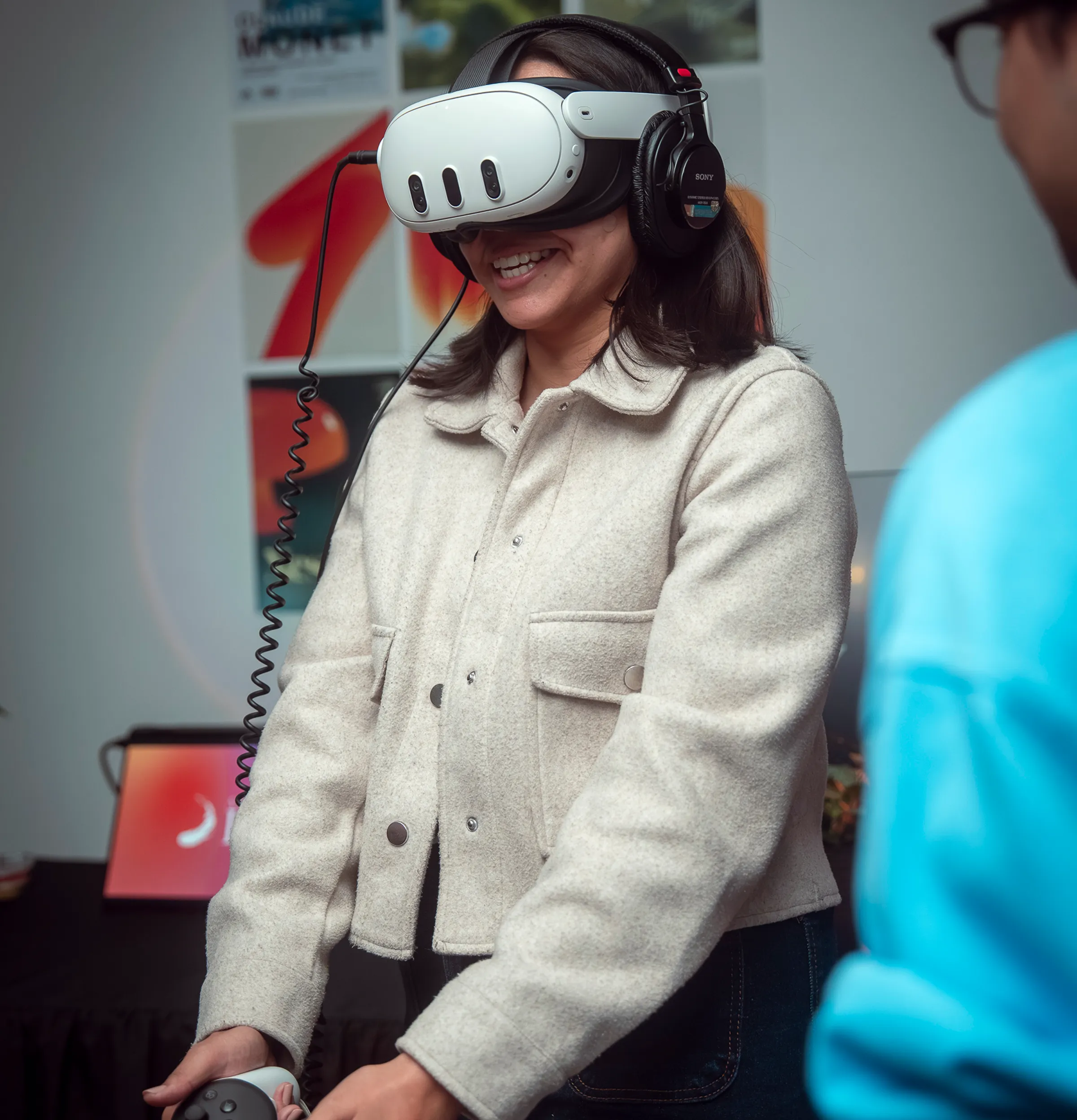 A visitor smiling inside the experience, Quest 3 and headphones on, at the NEXOS Exhibition